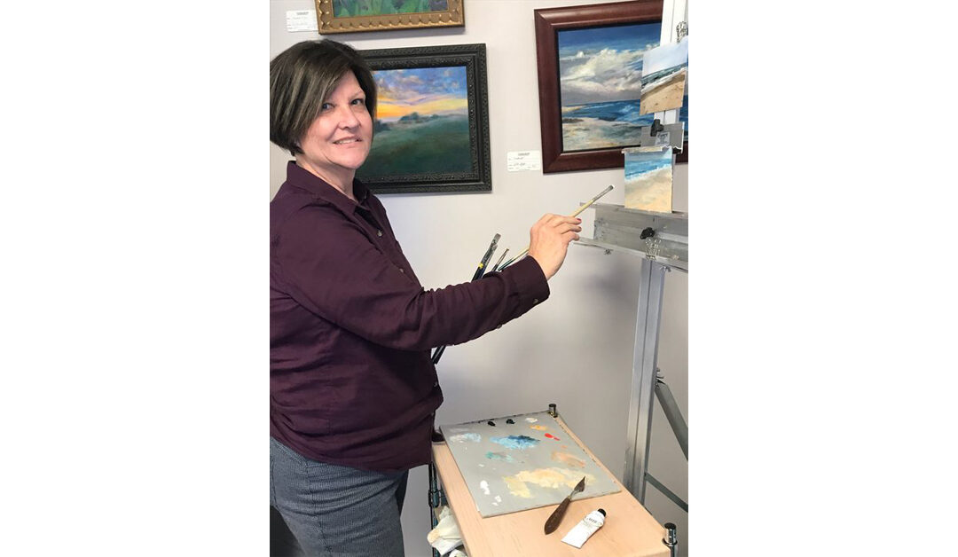 a woman at an easel creating an oil painting with paintings behind her