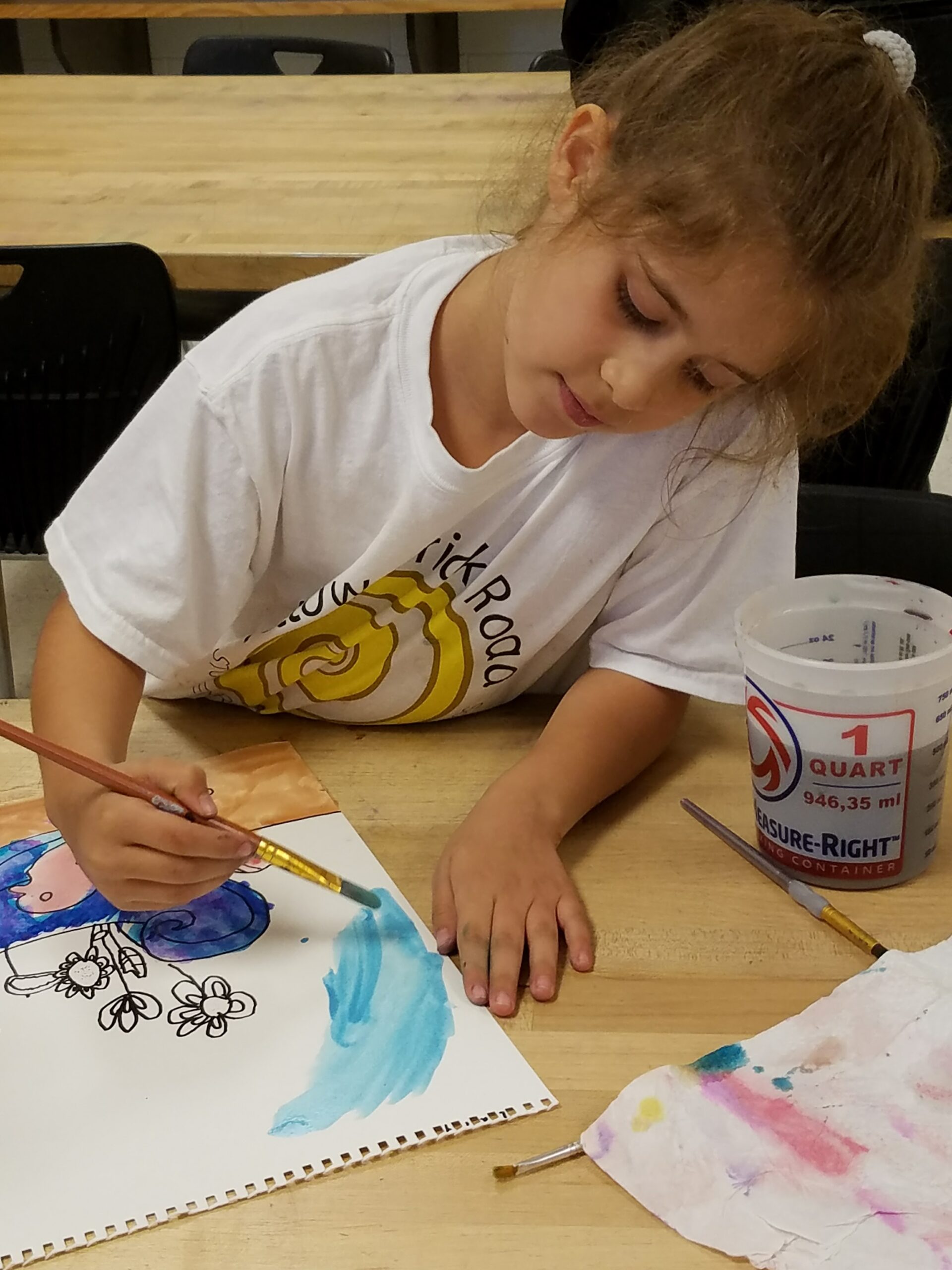 a child with a paintbrush painting with blue watercolor