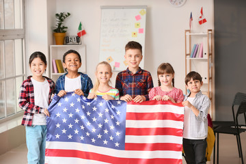 6 children holding a USA flag in a classroom