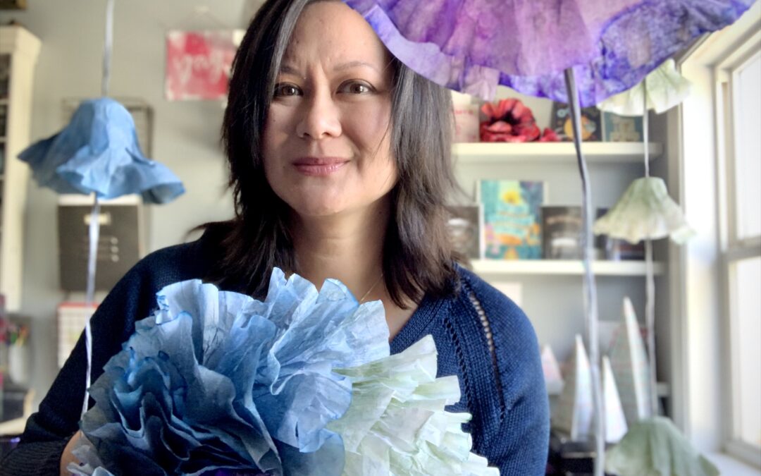 Michelle Jackson proudly displays vibrant tissue paper flowers, showcasing her creativity and artistic flair.